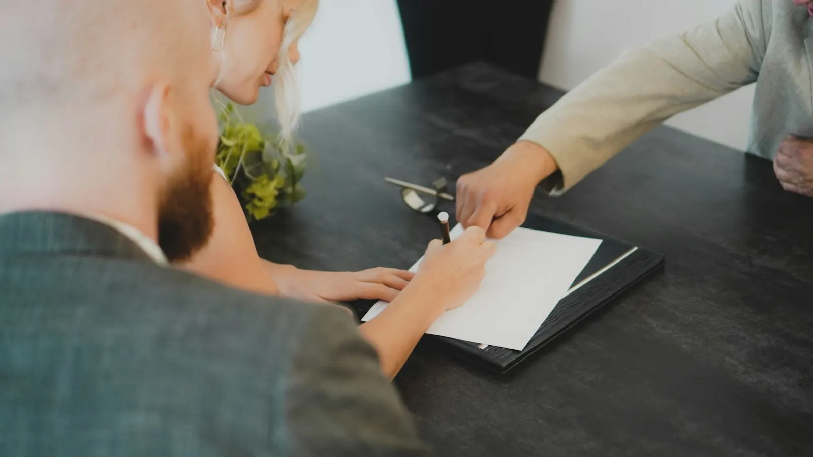 Dos personas firmando un documento en una mesa de despacho