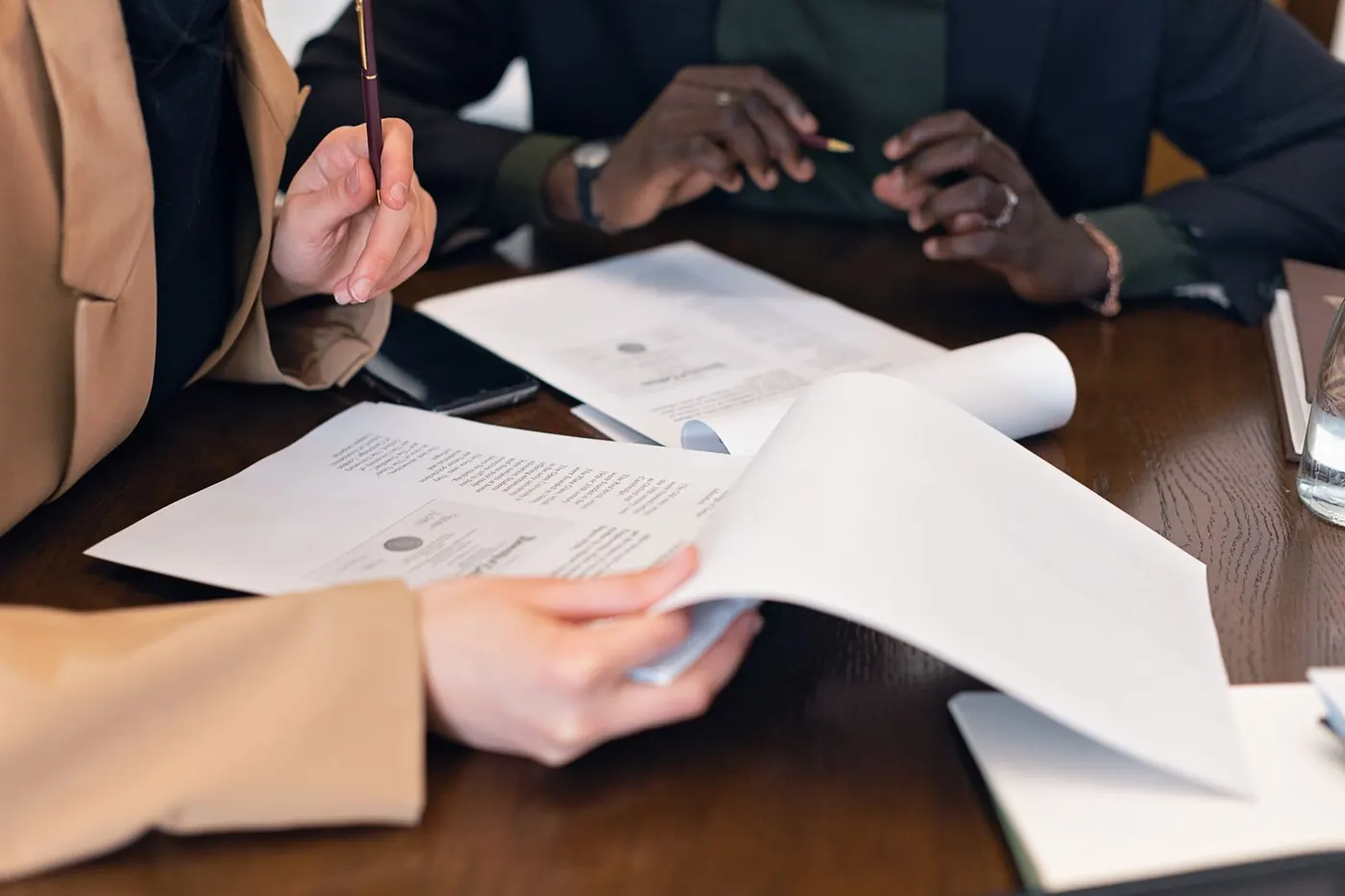 Primer plano de dos personas revisando documentos en una reunión