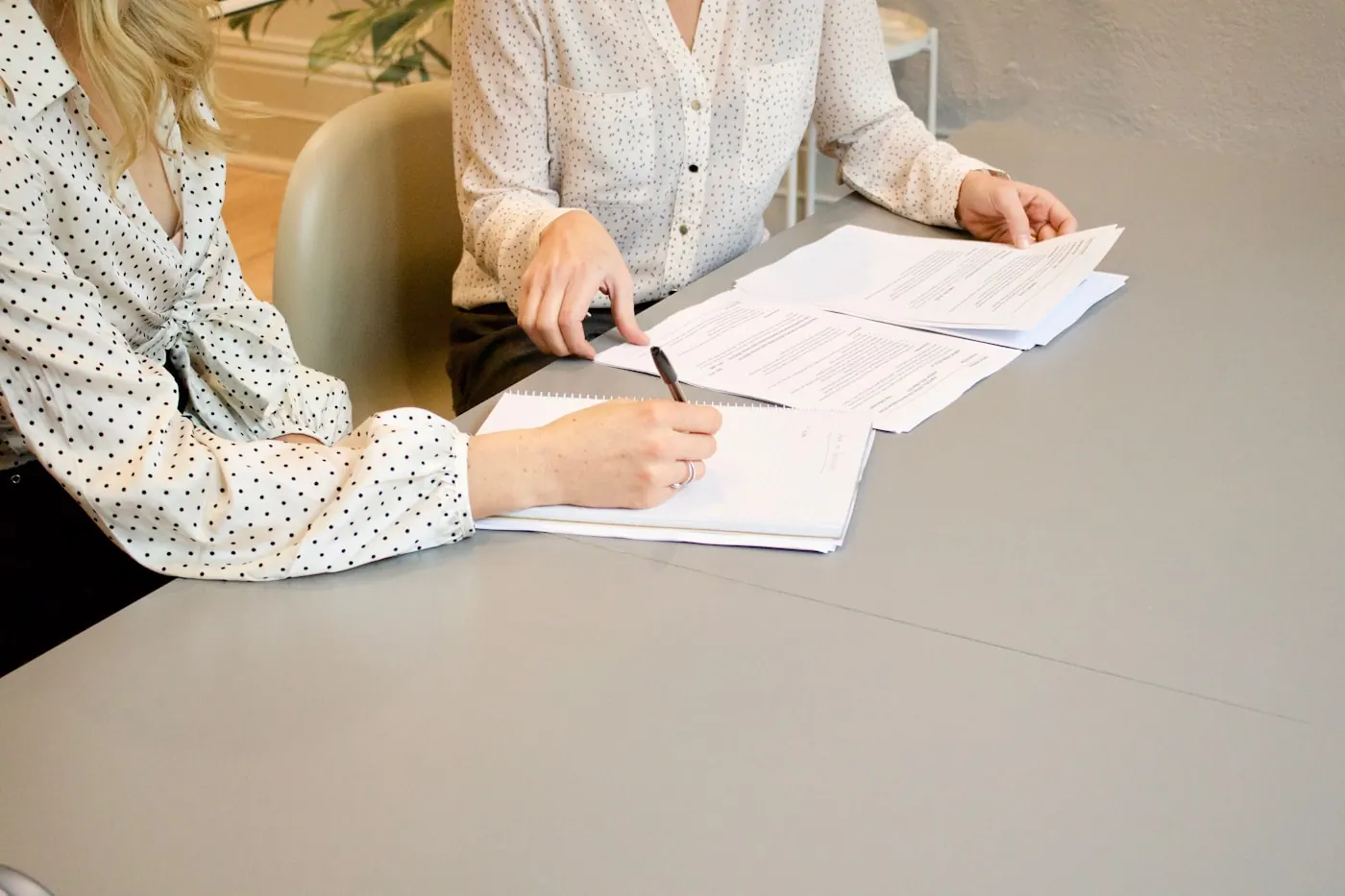 Dos personas revisando y firmando documentación sobre una mesa