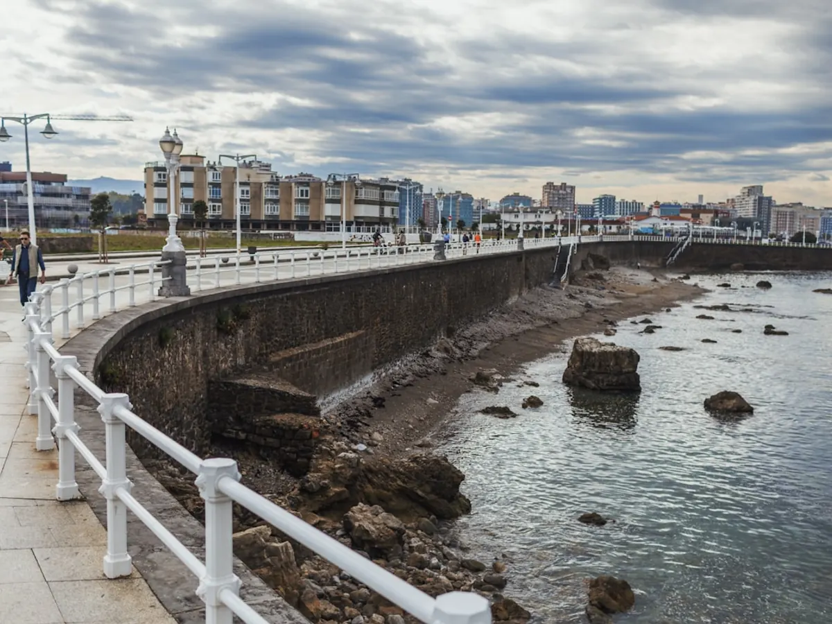 Paseo marítimo de Gijón junto al mar con los edificios de la ciudad al fondo